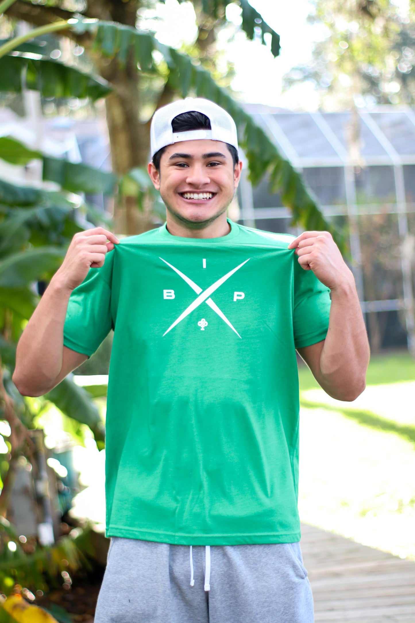 Introducing Nick Ireland wearing the Ireland Boys Productions merch ft X logo 2.0 in Cloud White printed on Kelly green NEXT LEVEL premium T-shirt